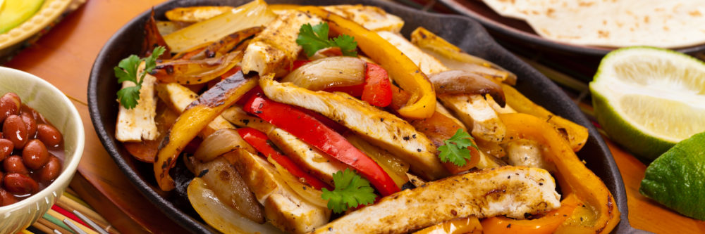 Chicken Fajitas with Grilled Onions and Bell Peppers serve with Tortillas. Selective focus.