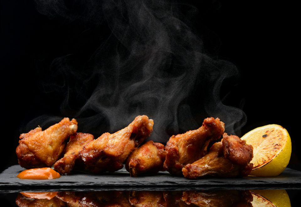 Hot and spicy bbq chicken wings with dip and hot sauce on black stone plate